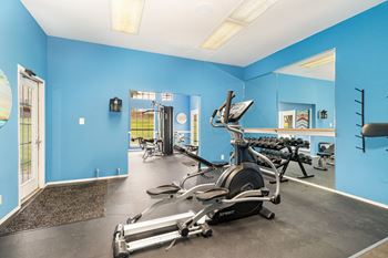 A gym with blue walls and a variety of exercise equipment.